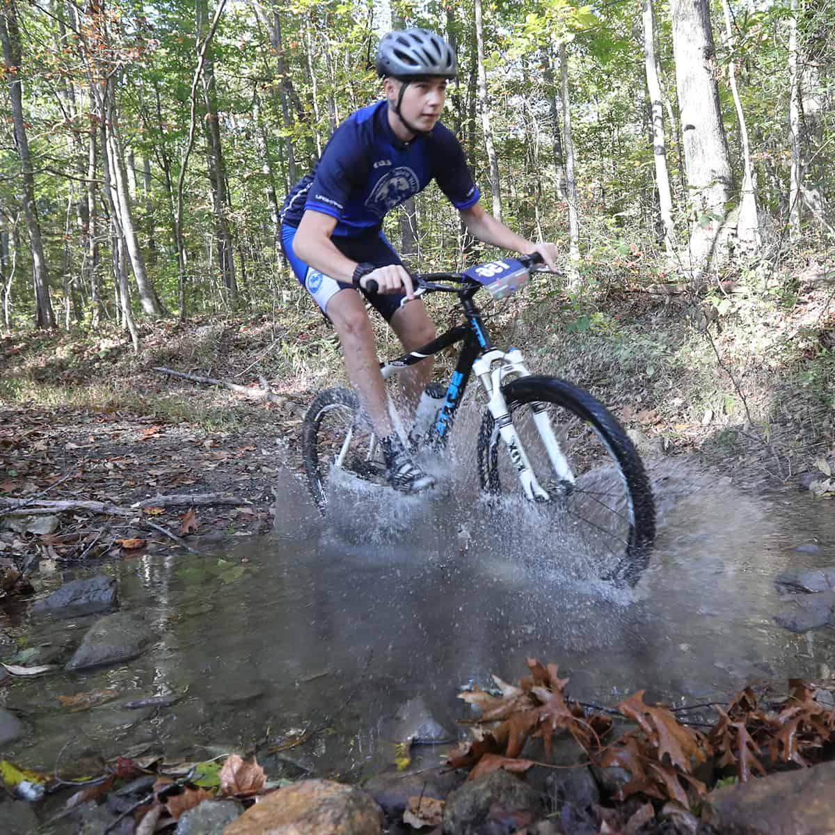 Mountain biker goes through a creek.